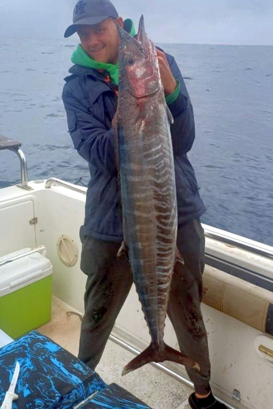 Deep sea angler holding a striped Wahoo caught offshore on a South Coast KZN fishing charter