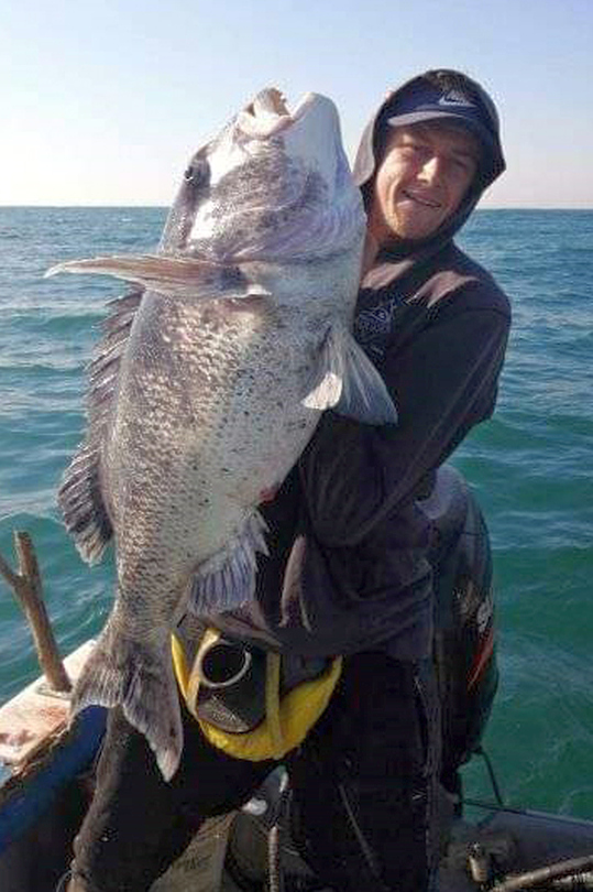 Angler on a fishing boat holding a large musselcracker caught off the South Coast KZN