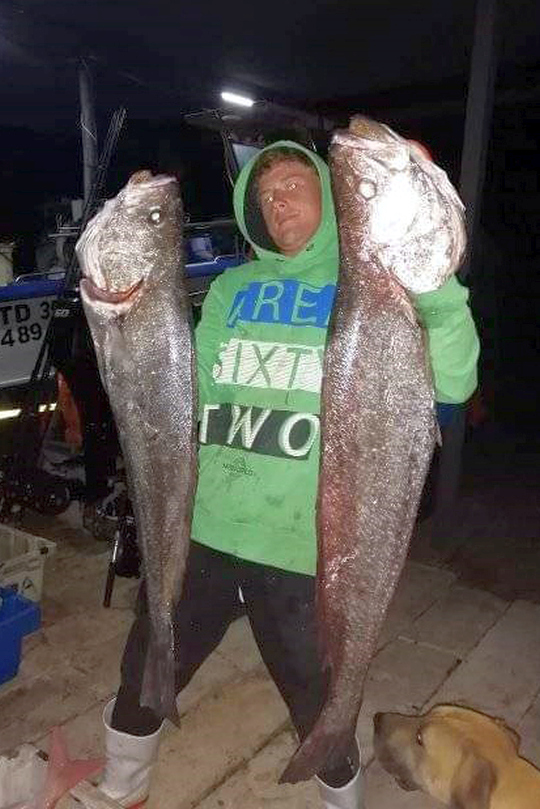 Angler holding two large kob caught during a night fishing session on the South Coast KZN