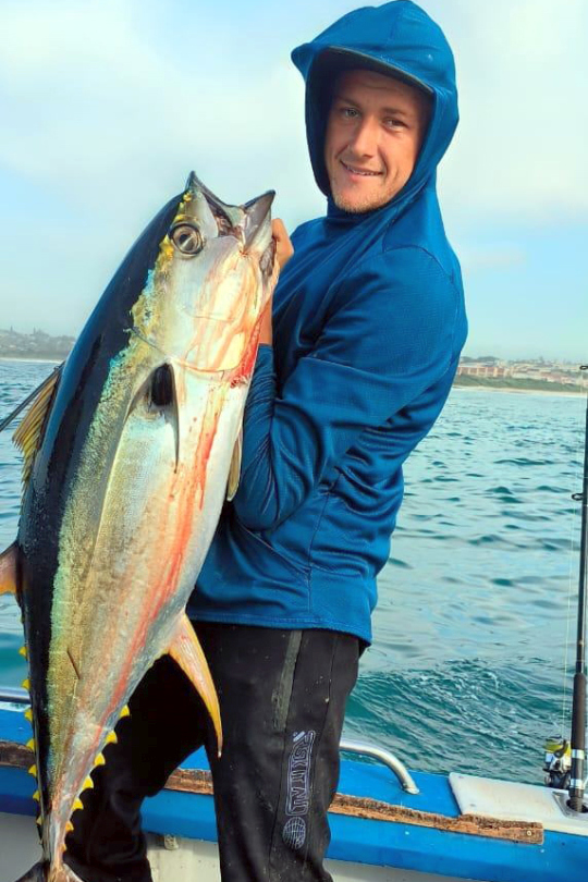 Angler holding a Yellowfin Tuna aboard a deep sea fishing charter off Shelly Beach, South Coast KZN
